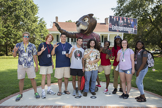 Students holding up J sign in front of Southpaw statue.