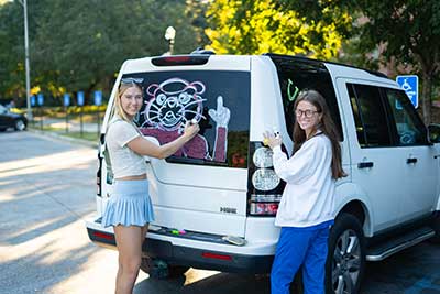 Students painting windows with Southpaw for homecoming.