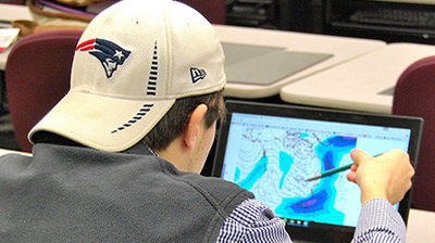 Student working at monitor on weather map.