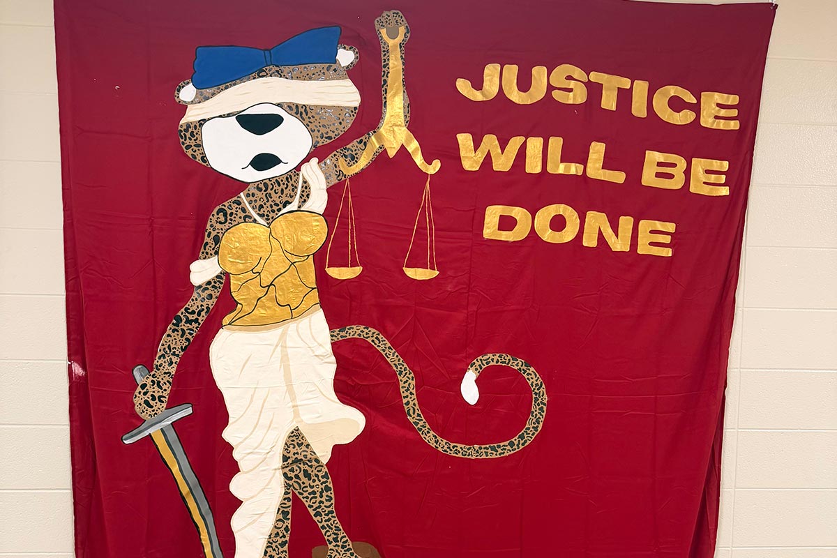 Ms Pawla holding up weight of justice with text Justice will be done.