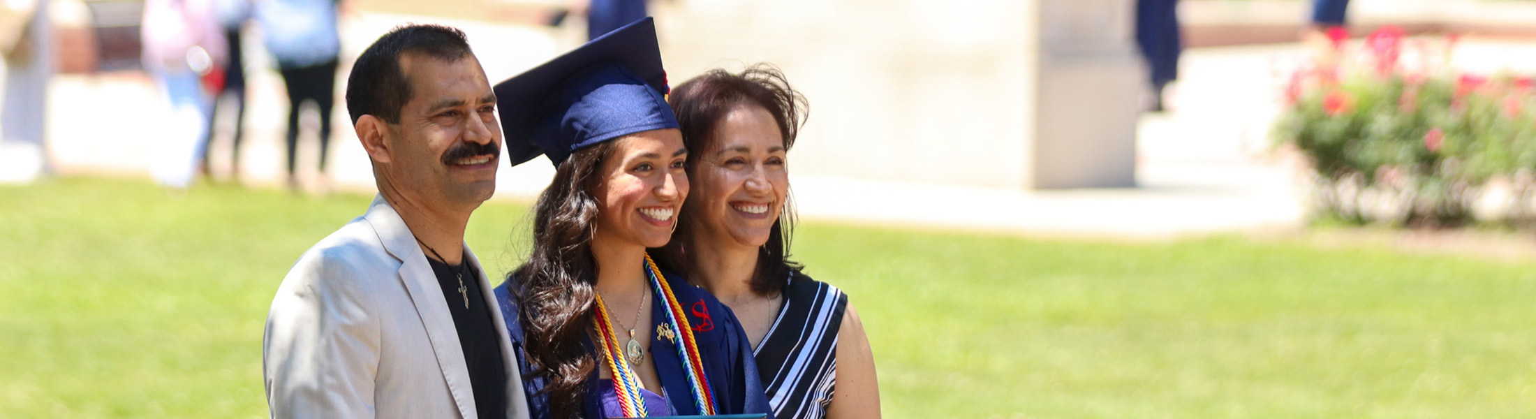 USA graduate in cap and gown with parents.